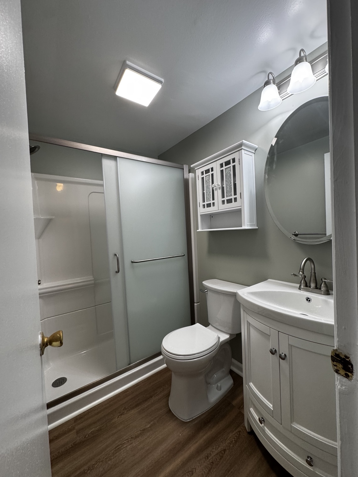 Completed bathroom remodel with a new shower, vanity, flooring, lighting, and fixtures
