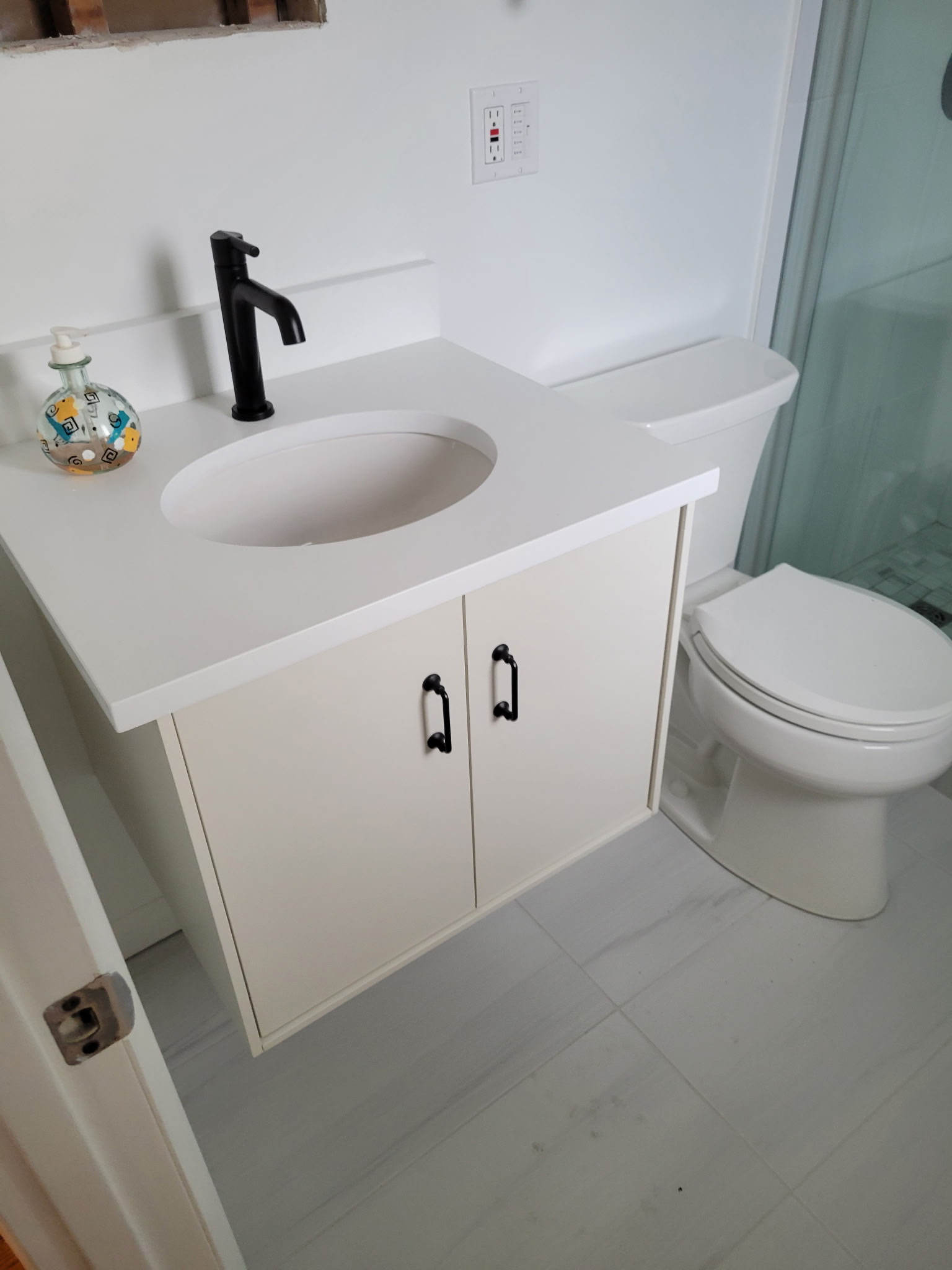 Updated bathroom with a white vanity, black faucet, toilet, and light flooring